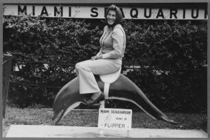 Frau auf einem Automaten-Delphin im Seaquarium, Miami