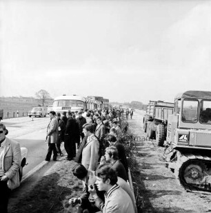 A 1: bei Stapelfeld: Verkehrsunfall: in Autobahnbaustelle: Auffahrunfall von zwei Bussen und einem Lastwagen: hinten Unfall-Busse und Unfall-Lkw hintereinander: davor auf Grünstreifen Busfahrgäste sitzend und stehend, Geländer: links Leitkegel, vorbeifahrende Autos: rechts Baustelle, Baufahrzeuge, 30. April 1969