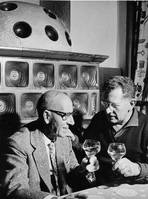 In einem Gasthof im Schwarzwald. Männer sitzen vor einem Ofen und trinken Wein