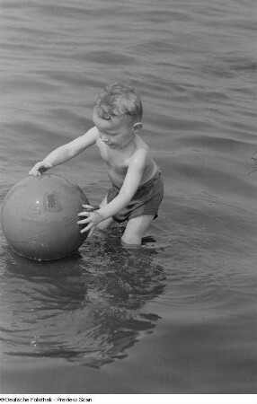 Kleiner Junge, mit einem Ball im Wasser spielend