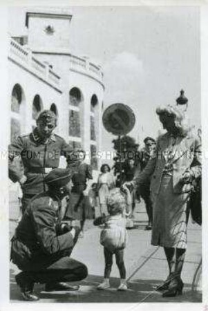 Zwei deutsche Soldaten sprechen mit einem kleinen Mädchen und seiner Mutter vor der Kirche Sacré-Coeur in Paris