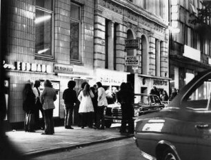 Hamburg. Adenauer Allee im Stadtteil St. Georg. Junge Menschen stehen vor einem Geschäft - einem berüchtigten Drogenkeller. Aufgenommen im Jahr 1971