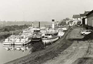 Dresden-Neustadt. Winterhafen des VEB Fahrgastschiffahrt "Weiße Flotte" Dresden. Blick auf abgestellte Motorschiffe, Dampfer und Landungsbrücken. Im Vordergrund Kaianlage des ehemaligen Verkehrshafens