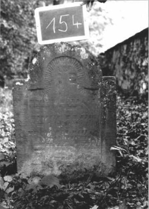 Grabstein 154 (Index: 99894860) Material: Sandstein Zustand: verwittert, im unteren Teil abgeblättert Maße HxBxT: 74x52x9 cm Beschreibung: Stele mit eingezogenem Rundbogenabschluss: Grabstein 154