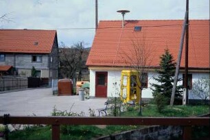 Haus der Gemeindeverwaltung; kleiner Platz mit Telefonzelle, Containerstellplatz