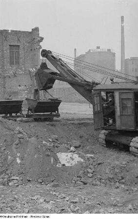 Blick auf eine Baustelle mit einem Bagger, der Loren befüllt