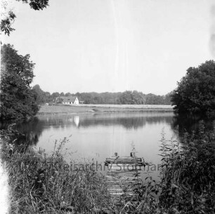 Tralau: Herrenhaus: Park: Teich: vorn Stauden und verfallener Bootssteg: links und rechts Bäume: hinten Haus und Wald