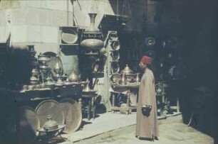 Reisefotos Ägypten.Verkaufsstand von Kupfergefäßen. Ansicht mit Mann im Kaftan und mit Fes