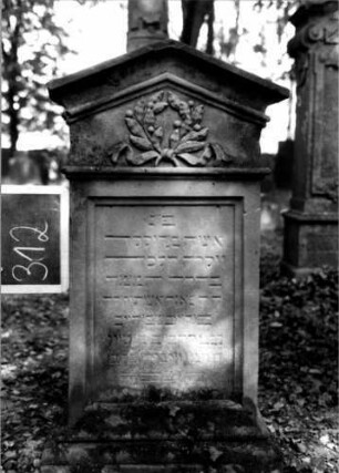 Grabstein 312 (Index: 100111992) Material: Sandstein Zustand: leicht verwittert Maße HxBxT: 110x55x25 cm Beschreibung: Stele, profilierter Sockel, giebelartiger Abschluß mit Verdachung, rechteckiges Schriftfeld eingetieft Symbolik: Kranz mit Schleife: Grabstein 312