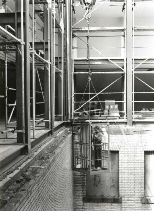 Dresden-Altstadt, Schloßplatz 1. Baustelle Ständehaus, Bauphase Substanzsicherung/Wiederaufbau Dach. Arbeitskorb, am Kranhaken angeschlagen und in einem Innenhof schwebend. Monteur bei Montage der Regenfallrohre