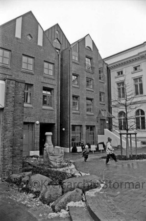 Hagenstraße: vorn links Brunnen: in der Mitte Kinder: hinten links Wohn- und Geschäftshäuser mit Durchgang zur Hindenburgstraße: hinten rechts Stadthaus