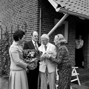 Hermann Claudius: Schriftsteller: geboren 19. Oktober 1878, gestorben 8. September 1980: 100. Geburtstag: vor Wohnhaus: Jubilar mit Ehefrau Gisela Claudius bei Begrüßung der Gratulanten Landesminister für Justiz Henning Schwarz und Ehefrau Gertrud Schwarz, mit Blumenstock: Klappstühle, an Haustür Frau, 19. Oktober 1978