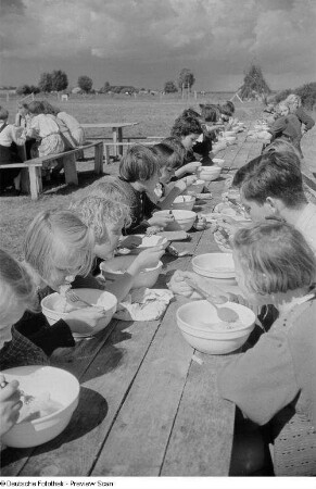 Kinder während des Essens an einer hölzernen Tafel im Freien