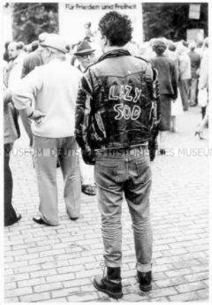 Rückenansicht eines Jugendlichen in Lederjacke mit der Aufschrift "Lazy Sod" (Altersgruppe 18-21)