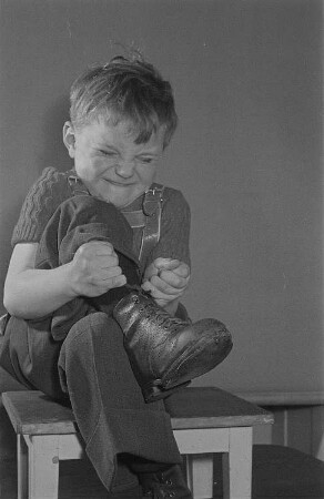 Ein Junge (Lothar) schnürt sich die Stiefel