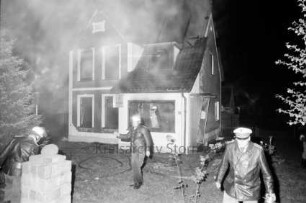 Brand: Zweifamilienhaus: vorn und im Haus Feuerwehrmänner: rechts Polizist: hinten Mitte Brandruine: Nacht