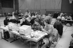 Stormarner Computer-Party "Copy-Inferno": Sporthalle der Joachim-Mähl-Schule: Jugendliche an Computern auf zusammengestellten Tischen: dazwischen und hinten stehende Jugendliche und Mann: 12. Januar 1992