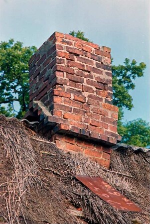 Düpenau (5): Haus mit Reetdach: Detailaufnahme: Schornstein, Schadstellen in Reetdeckung, Schild