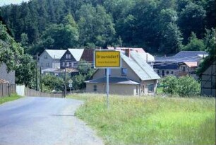 Ortseingang; abschüssige Straße, Häuser