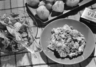Krafts Rezeptaufnahmen. Platte mit Pellkartoffeln und Teller mit Gemüse, wohl Blumenkohl mit Rahmkäse "Velveta". Daneben eine Schale mit grünem Salat