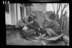 Odobești (=Rumänien): 2 Soldaten und 3 junge Rumänen vor einem Wohngebäude in der Hocke um ein kleines Feuer