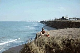 Eforie: Schwarzmeer Strand, Margarete Klein sitzt auf Böschung, Hintergrund Küste