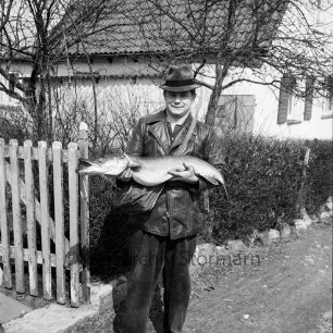 Strecker, Walter: geboren 1940: Einwohner von Reinfeld: vor Wohnhaus: mit Riesen-Hecht, Fang beim Angeln
