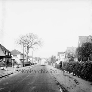 Tangstedter Straße: Ortseingang: rechts Ortsschild an Hecke: dahinter Bäume und Häuser: links Wohn- und Geschäftshäuser von Alwin Koltz und Elektro-Ahrens: hinten links Baum: hinten Mitte Lieferwagen
