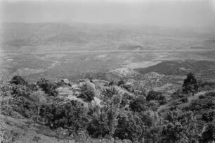 Dorf und Landschaftsblick : Blick über die Landschaft im Département de Tizi Ouzou. Zu sehen sind Getreidefelder unter Öl- und Feigenbäumen sowie Eichen, Eschen und Macchiebüsche, die sich in der Nähe eines kabylischen Dorfes oberhalb eines Tales befinden.