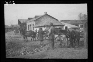Odobești (=Rumänien): 2 Pferdegespanne auf einem Platz vor einem landwirtschaftlichen Anwesen (Distanzaufnahme) ("Häuser")