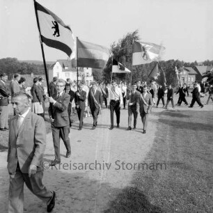 Kindervogelschießen: Umzug: Grünanlage zwischen Matthias-Claudius-Schule und Ahrensböker Straße (im Hintergrund): Fahnenträger: links Zuschauer, 24. Juni 1961