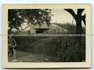 Wehrmachtssoldat mit Fahrrad vor einem Bunker im Elsass