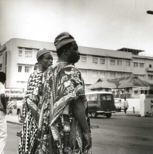 Lagos, Nigeria. Straßenszene im modernen Stadtteil mit Passanten in Festtracht