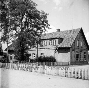 Volksschule: links davor Garten mit Baum: rechts Schulhof: vorn Zaun