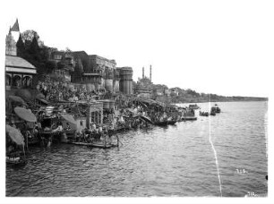 Varanasi (Benares), Indien. Pilgerstätte mit Tempelarchitektur am Ufer des Ganges gegen Minarette der Kleinen Moschee des Aurangzeb