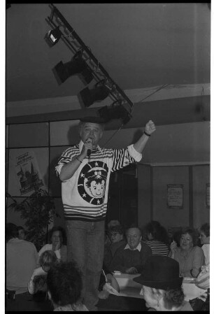 Stormarnia Ahrensburg 1989: Komiker Fips Asmussen steht auf einer Bühne vor Publikum und spricht ins Mikrofon