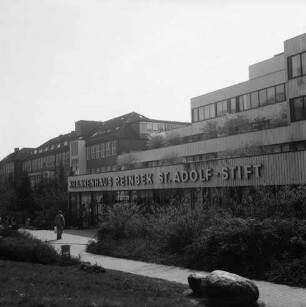 Krankenhäuser: Krankenhaus Reinbek St. Adolf-Stift: Hamburger Straße: Mittelbau mit Namenszug: davor Grünanlage mit Büschen, Bäumen sowie vorn rechts einer Plastik: links Mann: dahinter Altbau und Erweiterungsbau