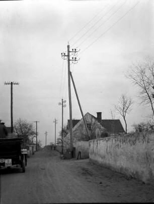 Sachsen? Erste 110 kV-Freileitung des Elektroarmaturenwerks Radebeul-Kötzschenbroda. Dorfstraße mit Leitungsmasten. Blick gegen Gehöft