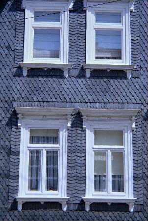 Hauswand mit Verschieferung und vier Fenstern
