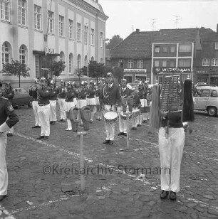 Oldesloer Spielmannszug e.V.: Markt: Entgegennahme der Standarte: Spielmannszug spielt: Parkuhren: links Postgebäude: hinten rechts an Hindenburgstraße Wohn- und Geschäftshaus, darin "Kleiderbad Buchholz", "Westbank"