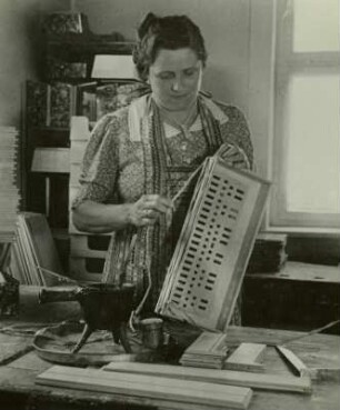 Akkordeonbau in Zwota-Zechenbach : Akkordeonbau in Zwota-Zechenbach, Akkordeonfabrik „Hutschelli“ Paul Hutschenreuter und Müller. Akkordeonbauerin beim Aufleimen des Zierstabes