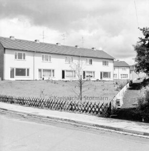Am Hohenkamp: vorn Jägerzaun und Grünfläche: rechts Fußweg: hinten Reihenhäuser