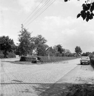 Hauptstraße: gepflasterte Fahrbahn, rechts parkender Pkw, links die Abzweigung zur Alten Dorfstraße, Blick Richtung Osten