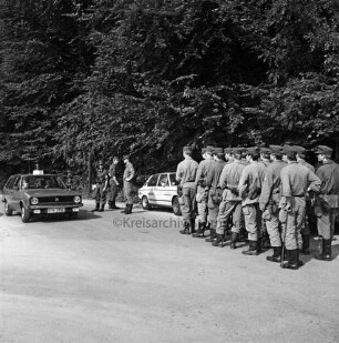 Polizei: Mord an Schülerin Marie Isabel Wellershaus am 19. Juni 1981: Krähenwald: Suchaktion der Bereitschaftspolizei Eutin nach Spuren: rechts angetretene Suchmannschaft: hinten Mitte mehrere Polizisten im Gespräch: rechts und links davon Pkws: dahinter Bäume
