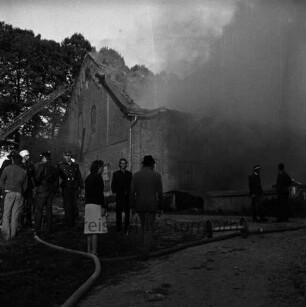 Gut Altfresenburg: Brand des Bullenstalls: Brandruine: Rauchschwaden aus eingestürztem Dach: vorn Feuerwehrleute und Helfer: hinten links Drehleiter an Giebel: dahinter Bäume: 24. August 1971