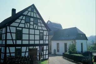 im Vordergrund die Giebelseite des Pfarrhauses, hinten Kirche