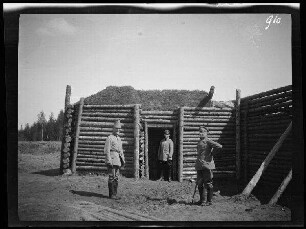 Komaika-Stellung (=Kamaja/Kamoja, Gewässer in Litauen): 3 Offiziere vor einem mit Palisaden befestigten Werk ("Stellungsausbau")