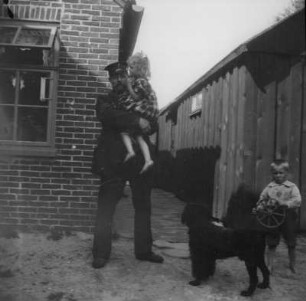 Spiekeroog. Uniformierter Mann mit zwei Kindern und einem Hund (vielleicht Mitglieder der Familie Jansen)