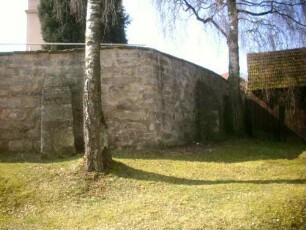 Ansicht von Nordosten - Kirchhofmauer über Feldseite (Wehrgang mit Steinbrüstung und Schießscharten im 19 Jh abgetragen)