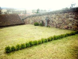 Kirchhof im Nordwesten mit ansteigender Kirchhofmauer (einstiger Wehrgang durch Regenabdeckung in Stein ersetzt)
